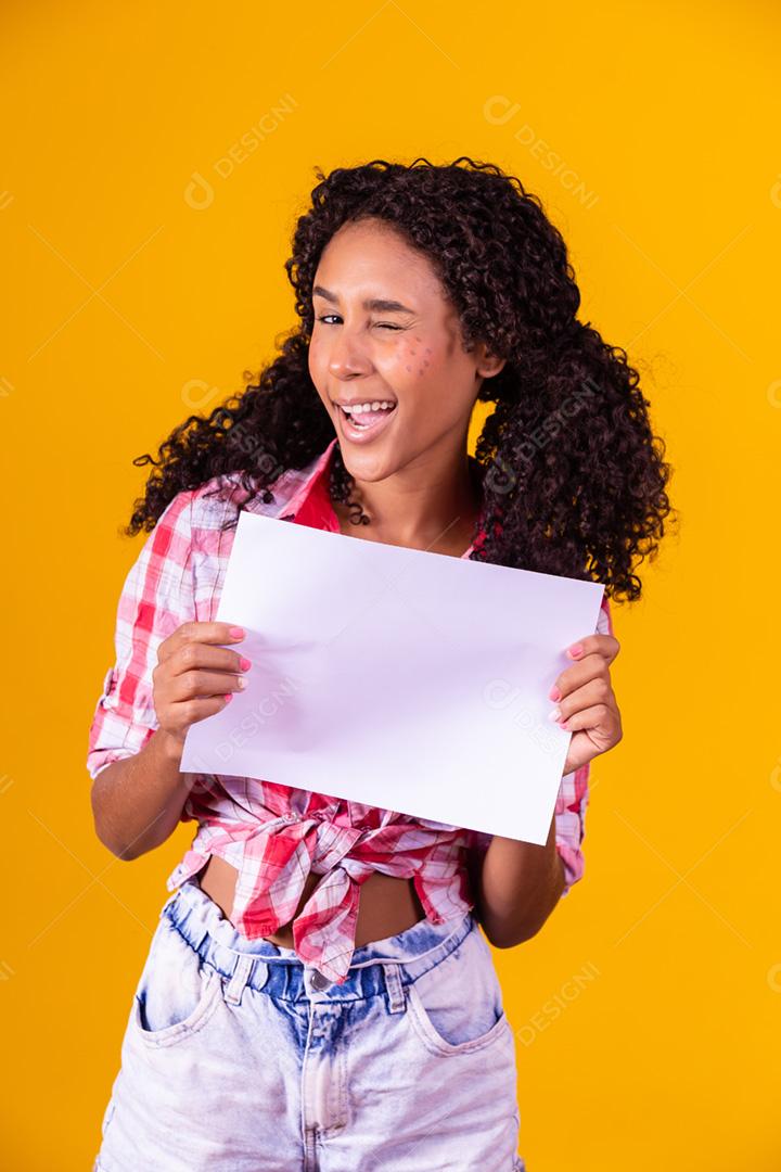 Mulher negra com roupa de festa junina segurando um cartão em branco para texto