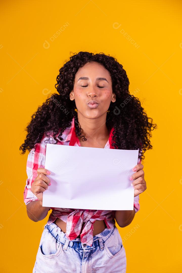 Mulher negra com roupa de festa junina segurando um cartão em branco para texto