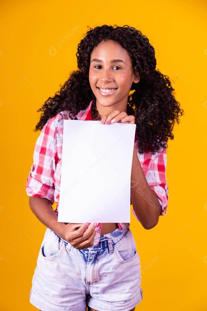 Mulher negra com roupa de festa junina segurando um cartão em branco para texto