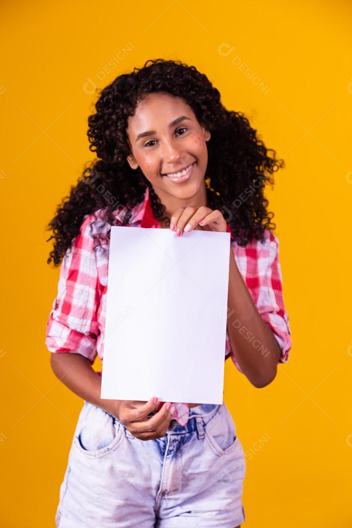 Mulher negra com roupa de festa junina segurando um cartão em branco para texto