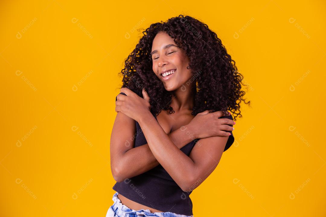 Mulher afro-americana com penteado afro e maquiagem glamourosa. Fundo amarelo.