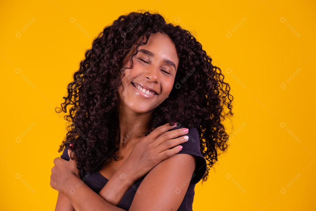 Mulher afro-americana com penteado afro e maquiagem glamourosa. Fundo amarelo.