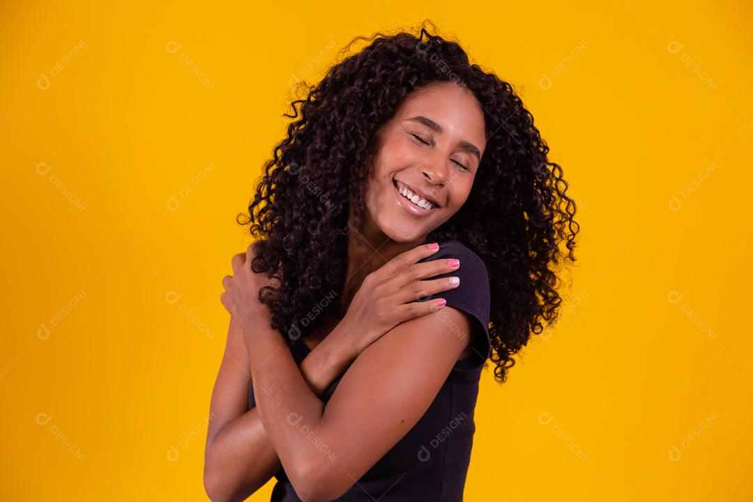 Mulher afro-americana com penteado afro e maquiagem glamourosa. Fundo amarelo.