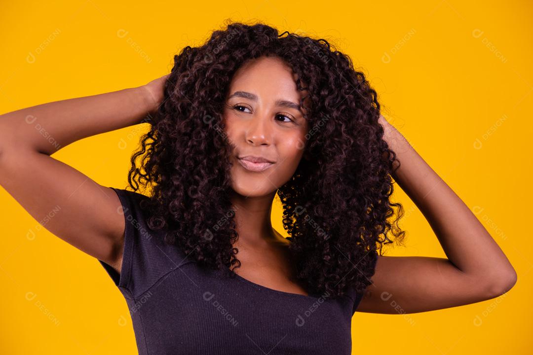 Mulher afro-americana com penteado afro e maquiagem glamourosa. Fundo amarelo.