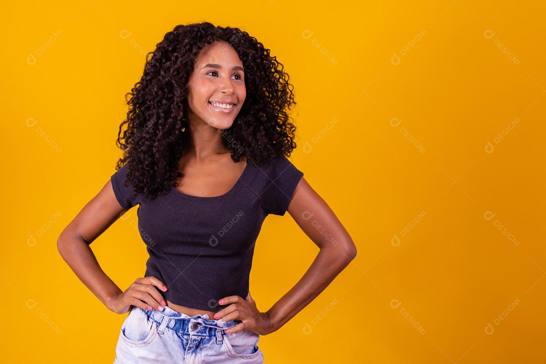 Mulher afro-americana com penteado afro e maquiagem glamourosa. Fundo amarelo.