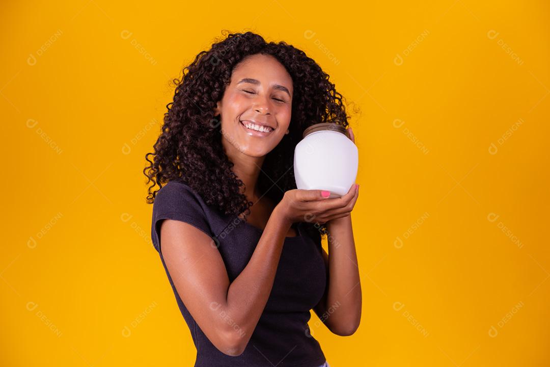 jovem afro segurando nas mãos um pacote de creme de cabelo