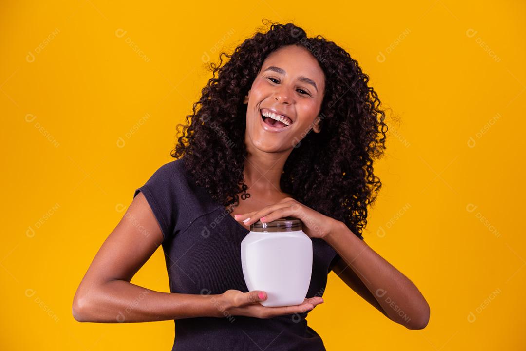 jovem afro segurando nas mãos um pacote de creme de cabelo