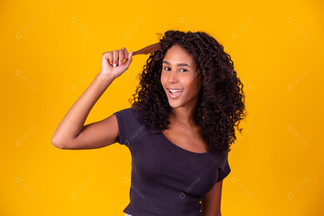 garota afro penteando o cabelo com um pente