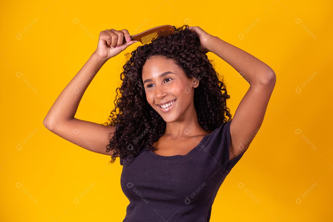 garota afro penteando o cabelo com um pente