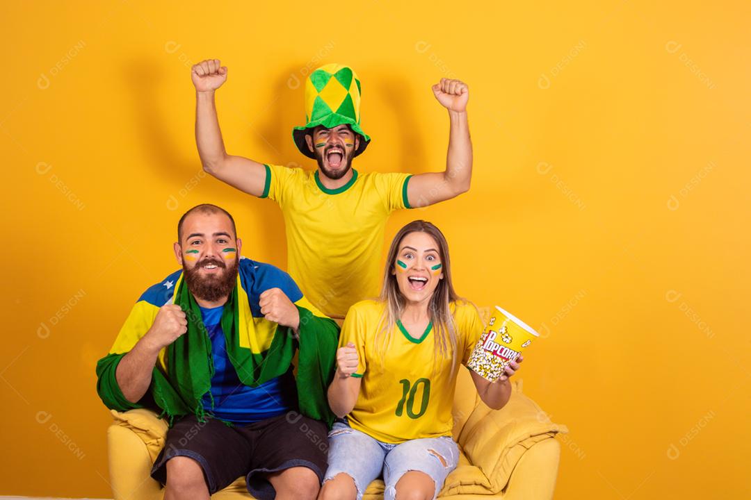 Grupo de amigos assistindo jogo de futebol na televisão, celebrando