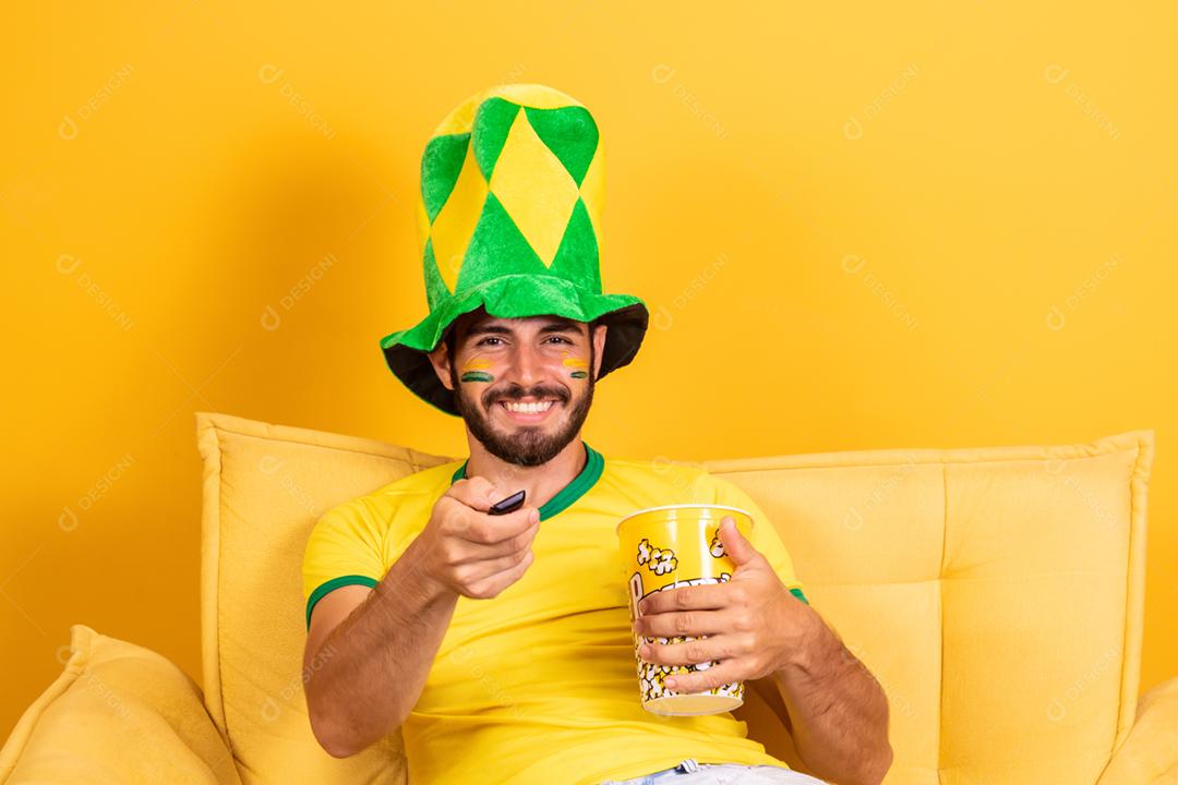 Jovem fã brasileiro assistindo o jogo na tv segurando um controle remoto
