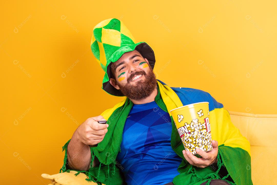 Jovem fã brasileiro assistindo o jogo na tv segurando um controle remoto