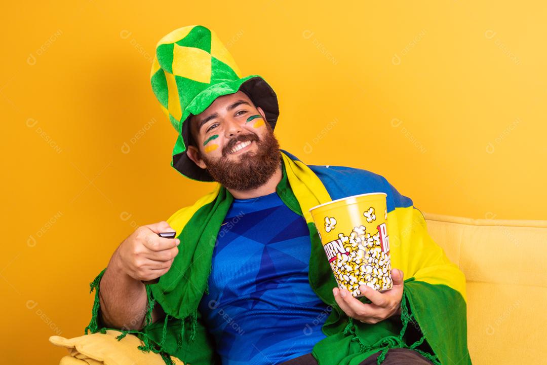 Jovem fã brasileiro assistindo o jogo na tv segurando um controle remoto