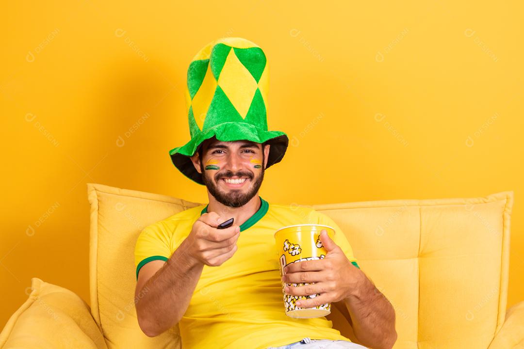 Jovem fã brasileiro assistindo o jogo na tv segurando um controle remoto