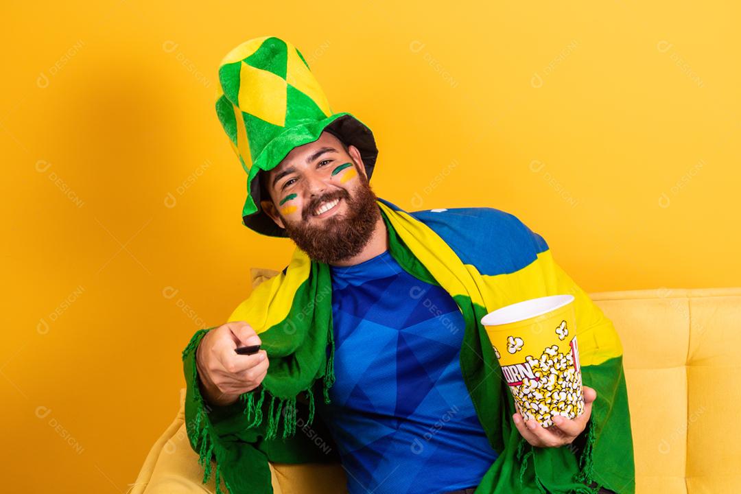 Jovem fã brasileiro assistindo o jogo na tv segurando um controle remoto