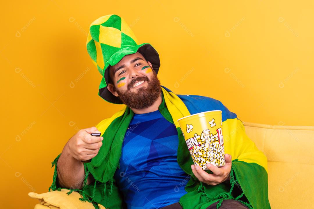 Jovem fã brasileiro assistindo o jogo na tv segurando um controle remoto