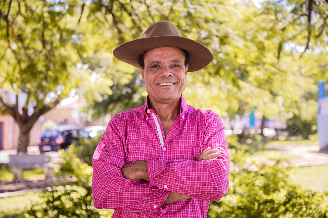 Retrato de sorridente agricultor masculino mais velho bonito. Agricultor idoso com braços cruzados sorrindo olhando para a câmera