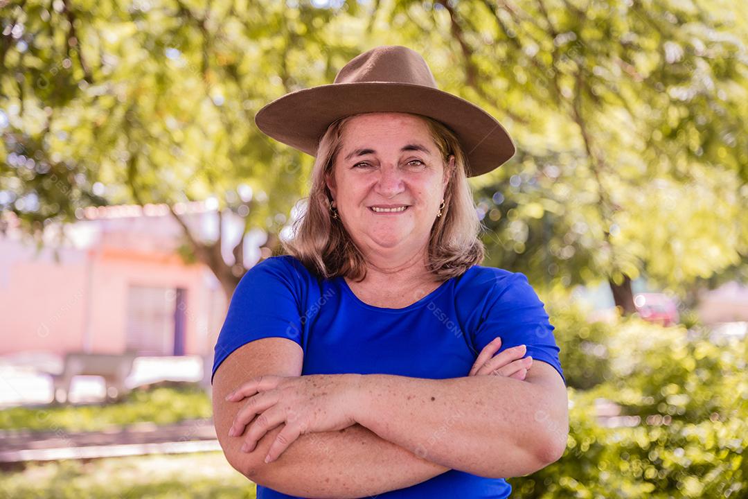 Agricultora feliz sorrindo para a câmera com os braços cruzados. Retrato de agricultor feminino lindo sorridente. Mulher na fazenda em dia de verão. Atividade de jardinagem. mulher idosa brasileira