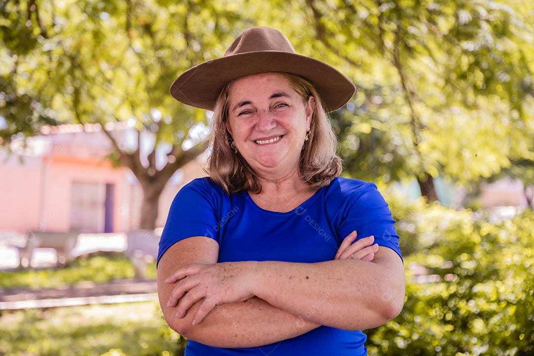 Agricultora feliz sorrindo para a câmera com os braços cruzados. Retrato de agricultor feminino lindo sorridente. Mulher na fazenda em dia de verão. Atividade de jardinagem. mulher idosa brasileira