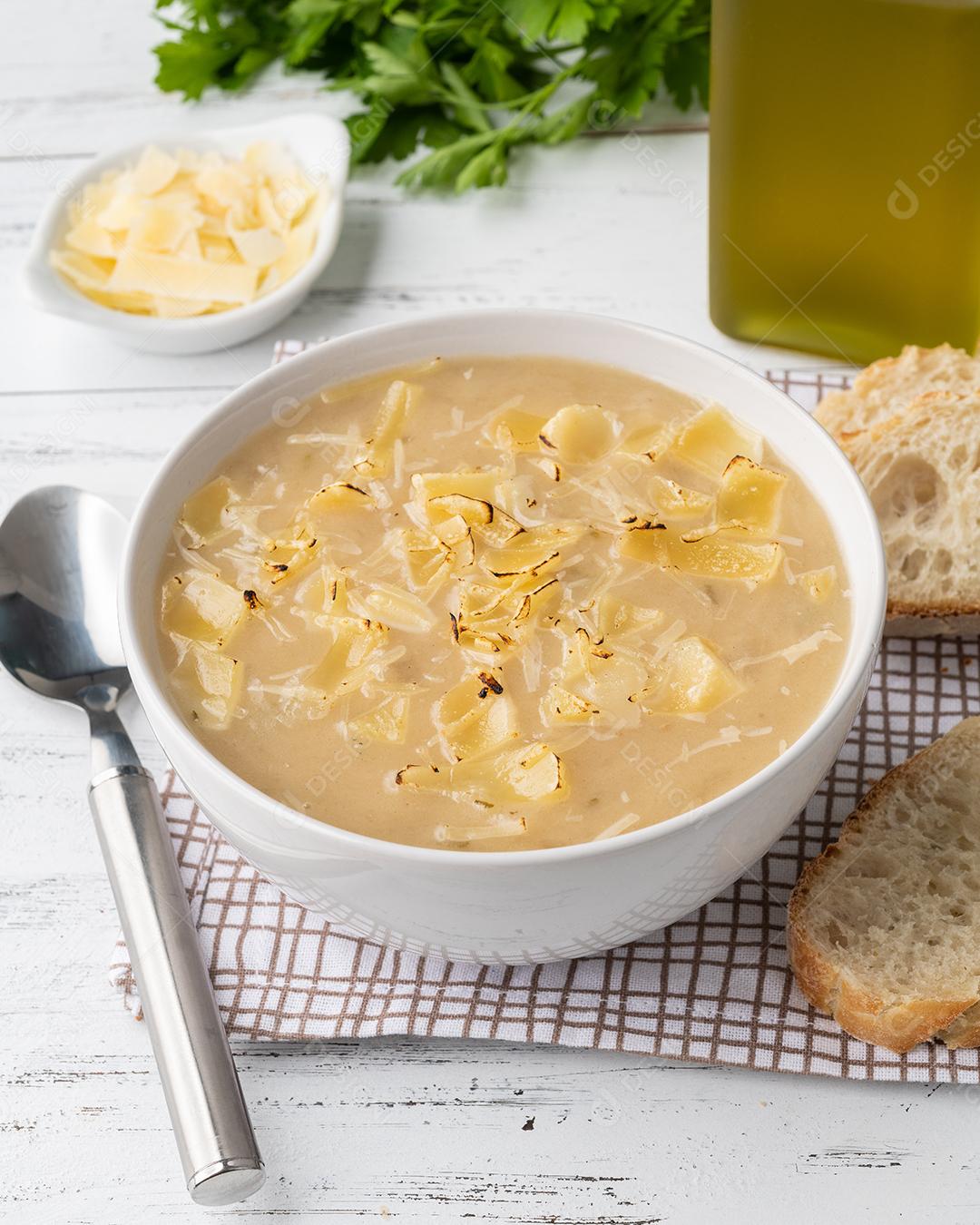 Sopa de cebola com queijo em uma tigela com fatias de pão e temperos