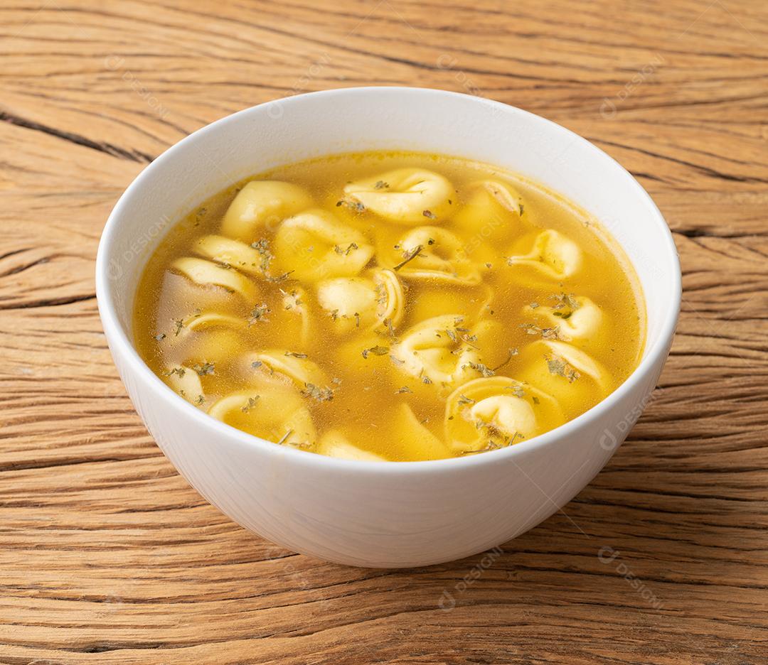 Sopa de cappelletti ou tortellini brodo em uma tigela com fatias de pão