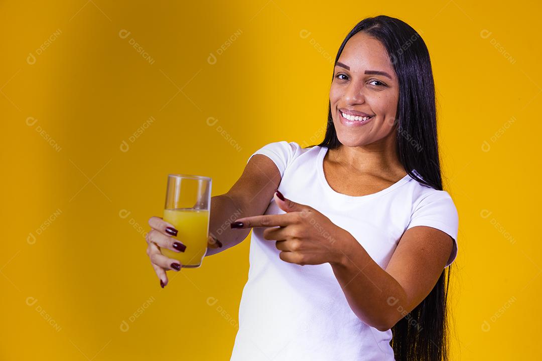 mulher bebendo suco de laranja em fundo amarelo