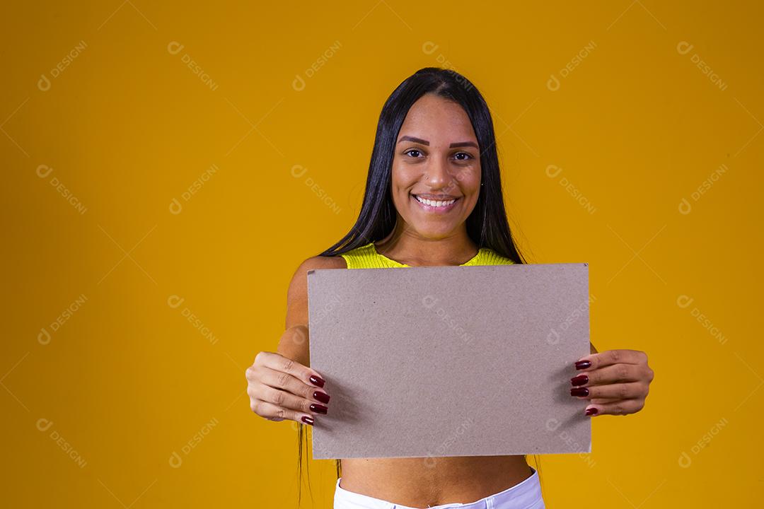 Linda mulher segurando outdoor em branco isolado em fundo amarelo