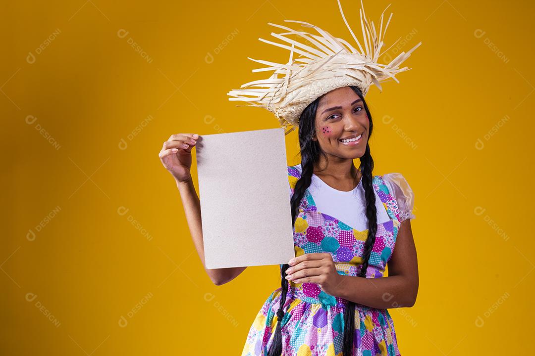 Linda mulher vestida com roupa de festa junina segurando uma placa em branco