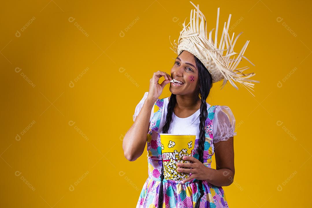 Linda mulher vestida com roupa de festa junina comendo pipoca