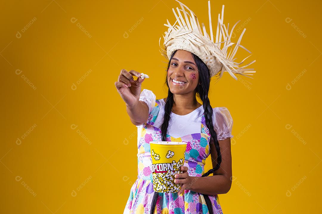 Linda mulher vestida com roupa de festa junina comendo pipoca