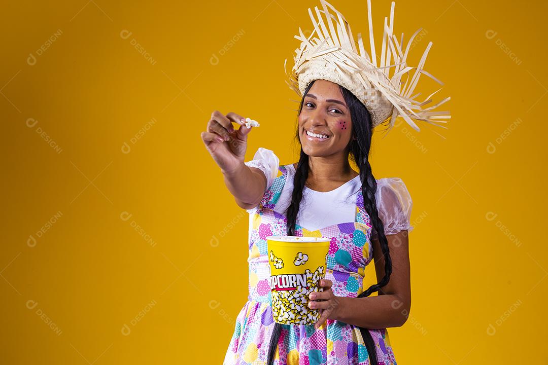 Linda mulher vestida com roupa de festa junina comendo pipoca