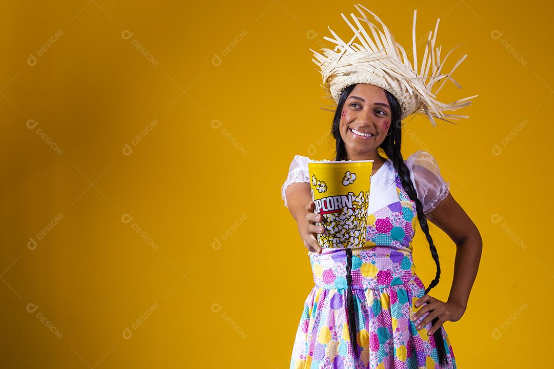 Linda mulher vestida com roupa de festa junina comendo pipoca