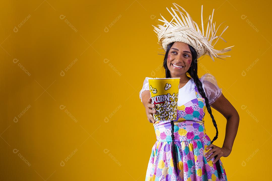 Linda mulher vestida com roupa de festa junina comendo pipoca