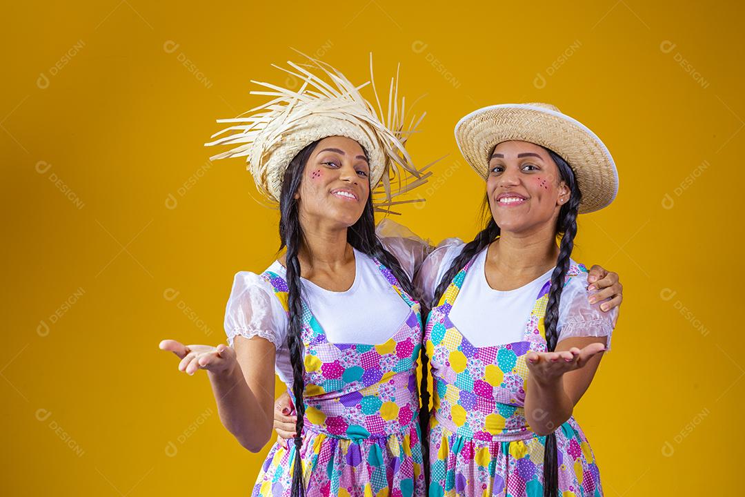 Irmãs gêmeas idênticas vestindo roupas tradicionais para Festa Junina - festival de junho