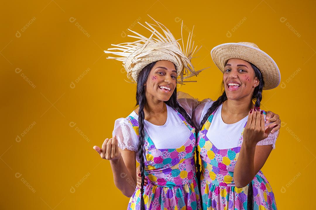 Irmãs gêmeas idênticas vestindo roupas tradicionais para Festa Junina - festival de junho