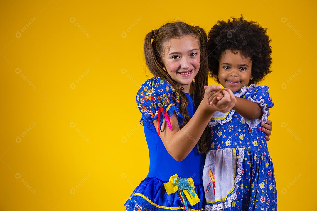 Crianças em roupas típicas da famosa festa brasileira chamada Festa Junina em comemoração ao São João dançando