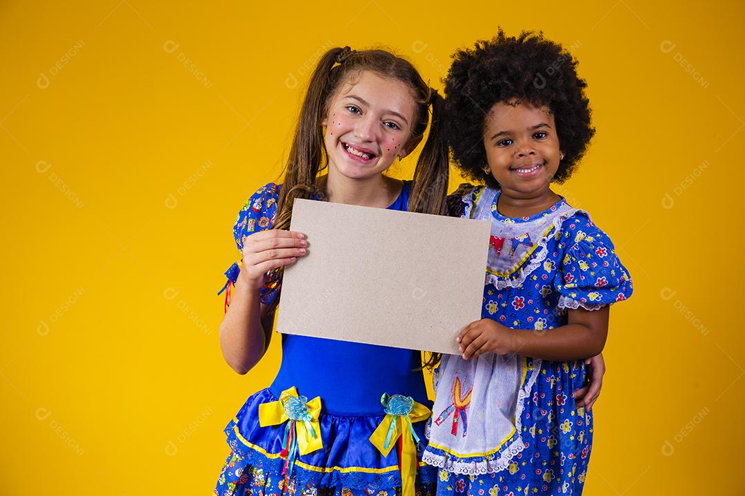 Two children friends in June party outfits holding a blank card