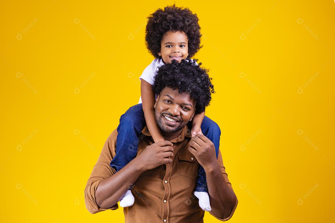 Afro father and daughter on yellow background smiling and playing. Father's Day Concept