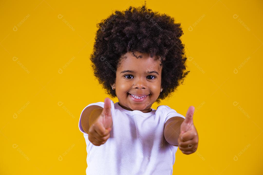 infância, gesto e conceito de pessoas - menina afro feliz mostrando os polegares sobre fundo amarelo