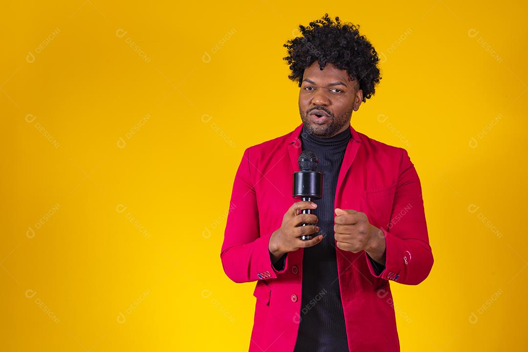 Alegre negro milenar segurando microfone e cantando para a câmera, jovem alegre hipster afro-americano