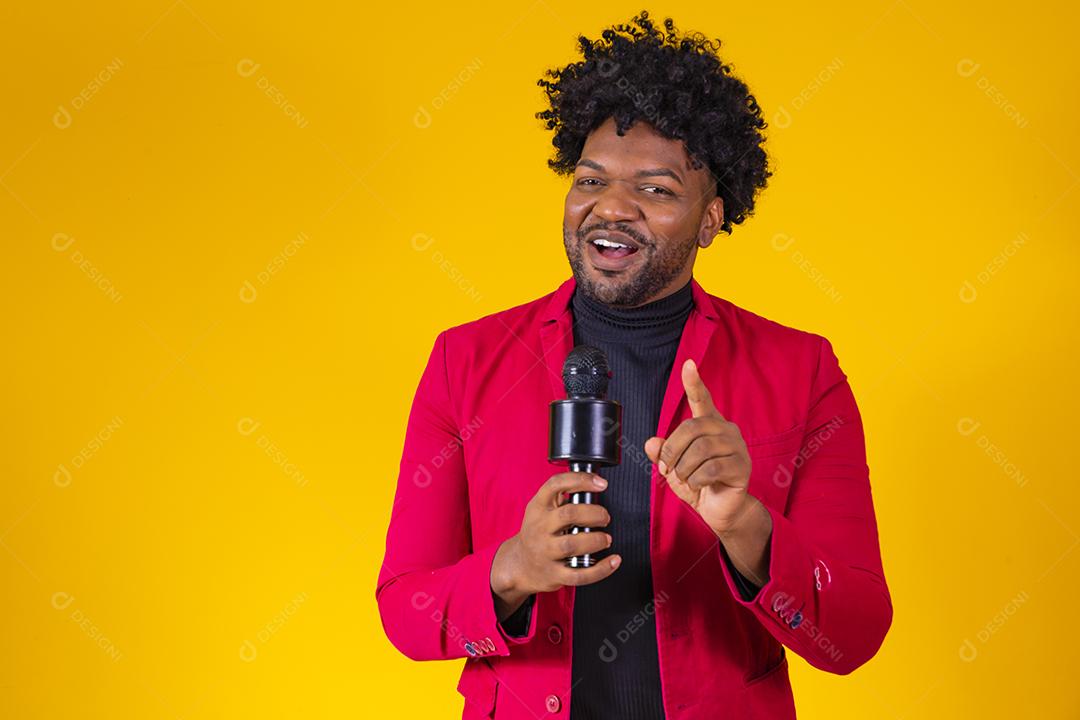 Alegre negro milenar segurando microfone e cantando para a câmera, jovem alegre hipster afro-americano