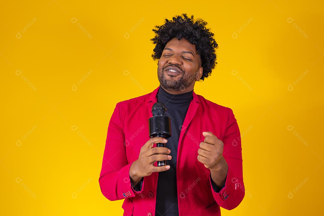 Alegre negro milenar segurando microfone e cantando para a câmera, jovem alegre hipster