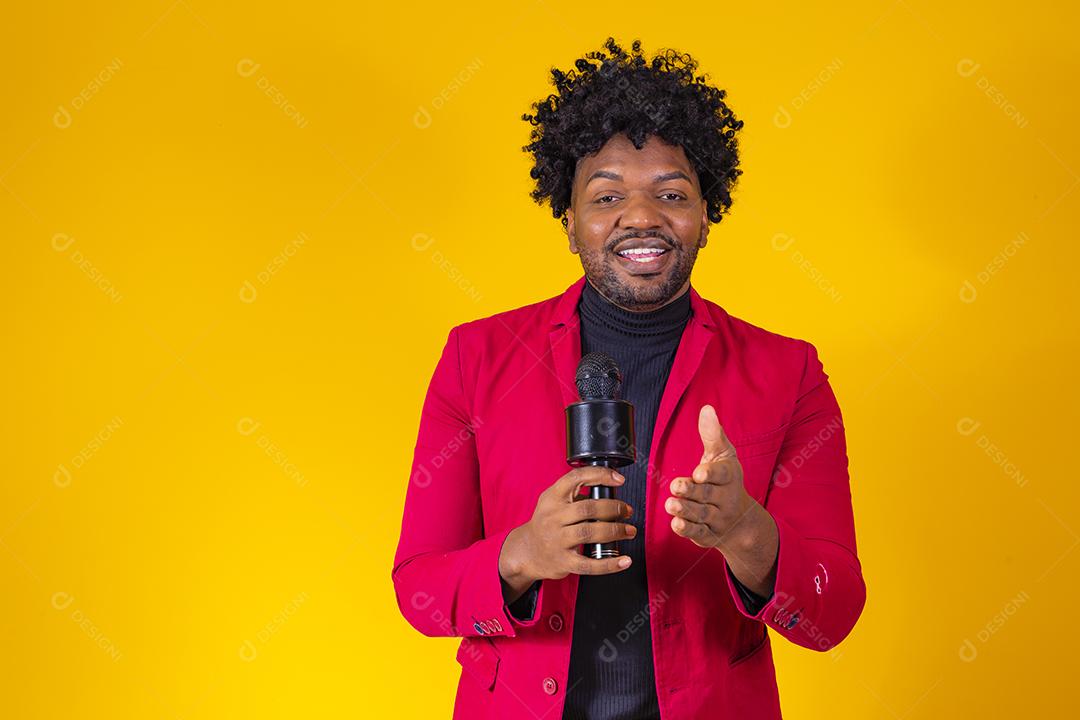 Alegre negro milenar segurando microfone e cantando para a câmera, jovem alegre hipster