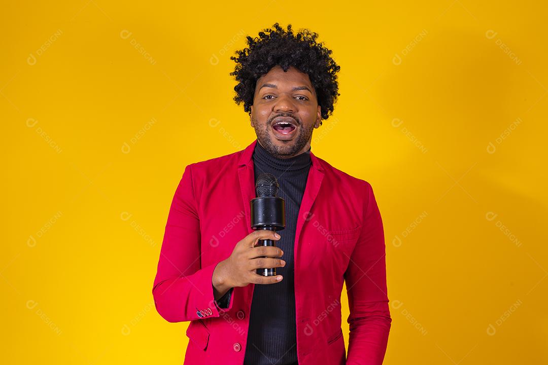 Alegre negro milenar segurando microfone e cantando para a câmera, jovem alegre hipster