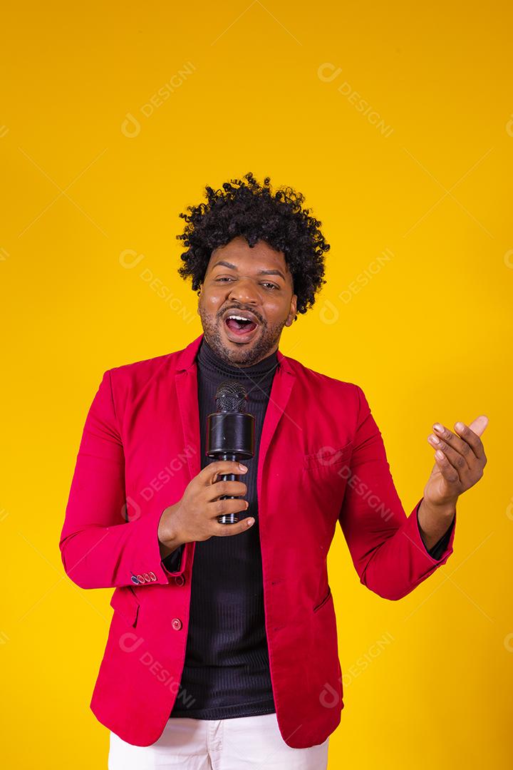 Alegre negro milenar segurando microfone e cantando para a câmera, jovem alegre hipster