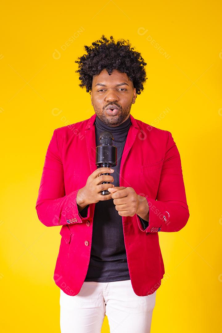 Alegre negro milenar segurando microfone e cantando para a câmera, jovem alegre hipster