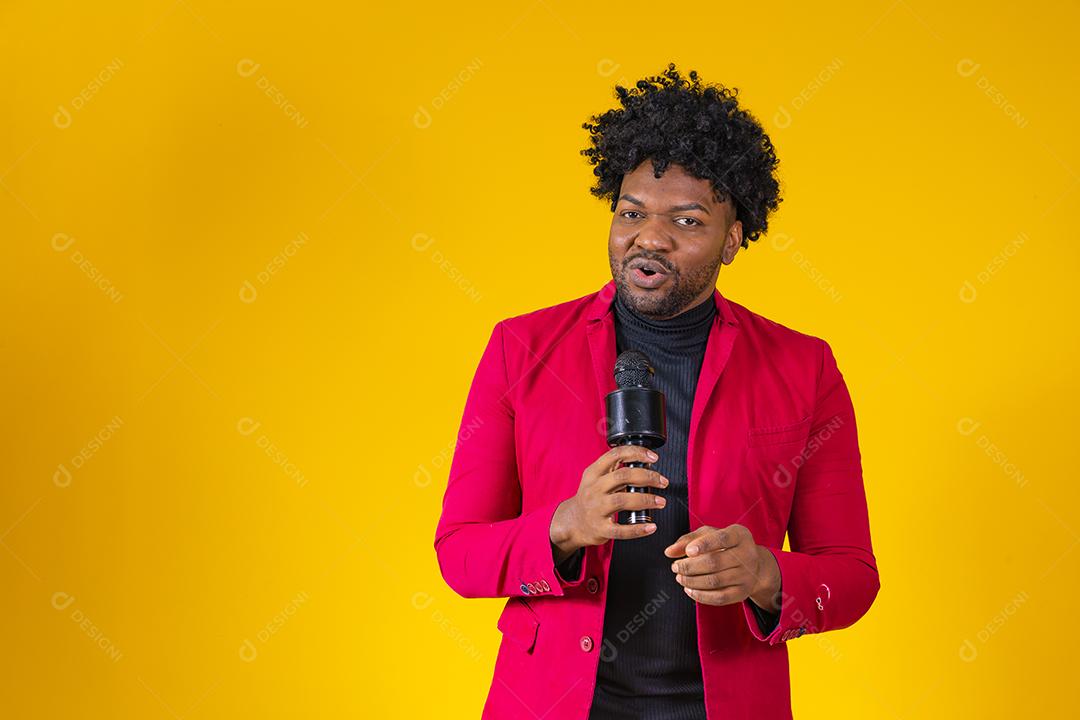 Alegre negro milenar segurando microfone e cantando para a câmera, jovem alegre hipster