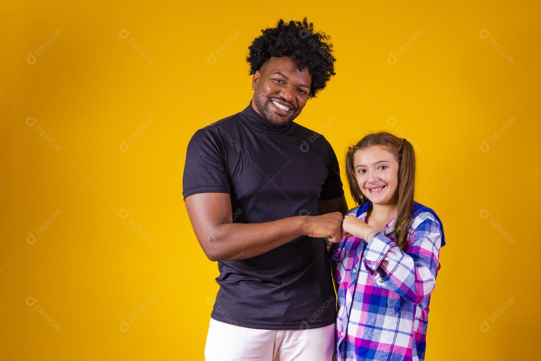 pai e filha em fundo amarelo comemorando a vitória. Pai e filha fazendo sinal de sim