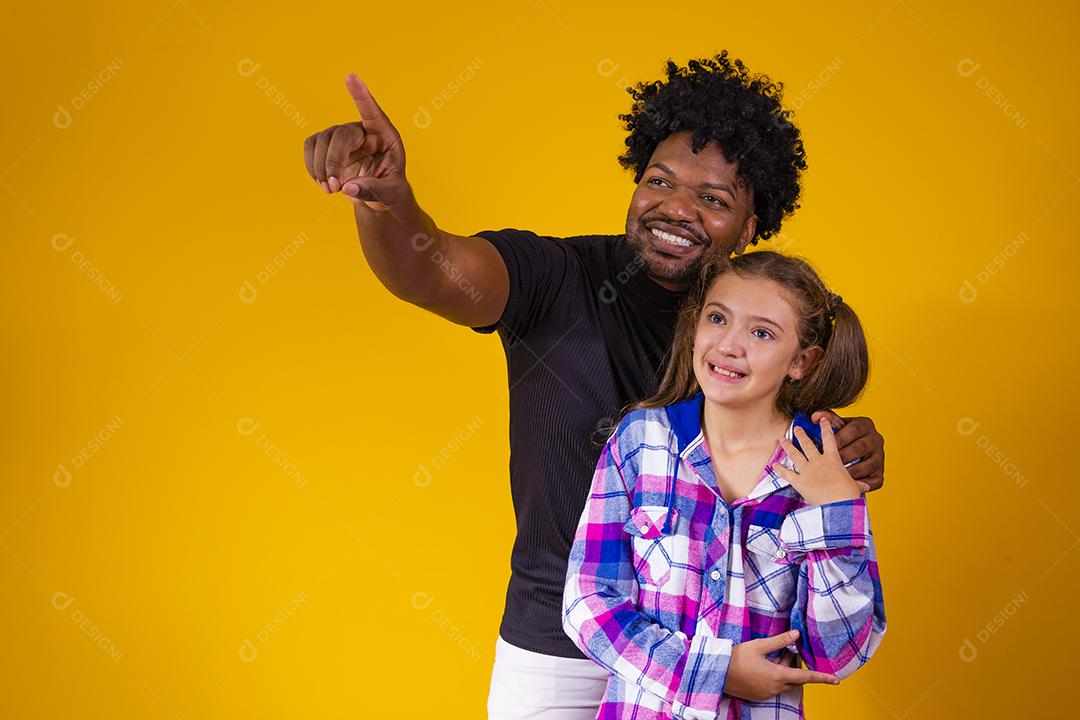 pai e filha em fundo amarelo Pai aponta para o horizonte mostrando algo para sua filha.
