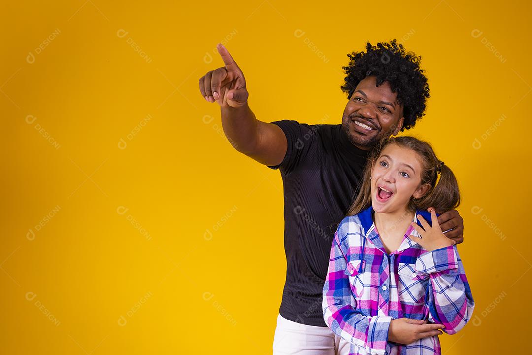 pai e filha em fundo amarelo Pai aponta para o horizonte mostrando algo para sua filha.